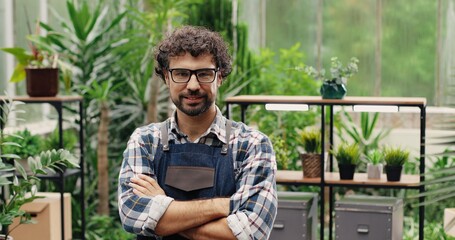 Close up portrait of happy handsome Caucasian businessman standing in apron in own flower shop and...
