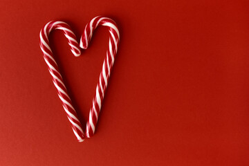Merry Christmas and Happy New Year greeting card. Xmas holiday red background. Heart made of candy