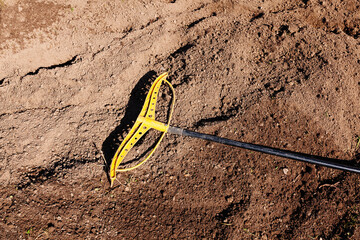 Bright yellow garden rake lying on fresh soil in garden