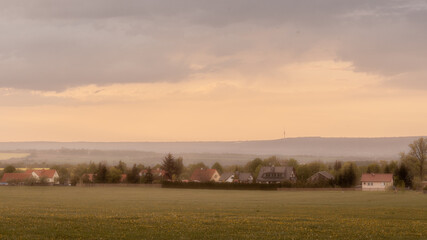 Countryside landscape of rolling hills, old farm, houses, all bathed in yellow sunlight (Germany).