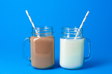 Glass jar with fresh milk against blue background