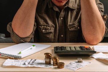 Man clutched his head calculating taxes and conducting accounting, receipts and a calculator are...
