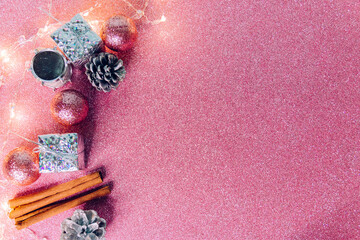 Flatlay with decorative holiday decorations for Christmas and New year on a pink sparkling background with a copyspace. Selective focus