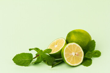 Lime with mint leaves isolated on light green background.
