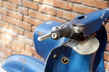 Close-up a left handle of the vintage motocylcy beside a vintage red brick wall.