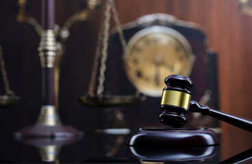 Law concept. Judge wooden gavel, scale and old clock  on brown background.