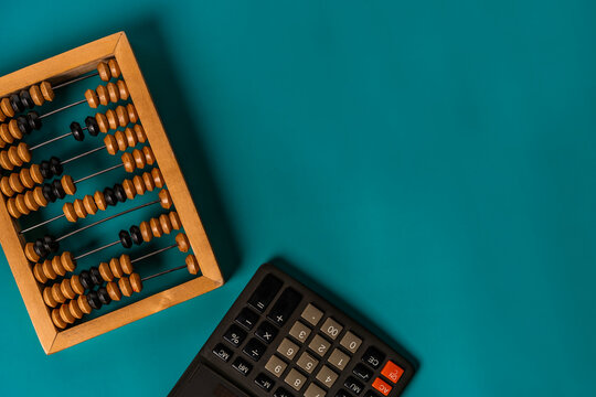 Top view of vintage abacus and modern calculator on a green background, the concept of finance and mathematical calculations