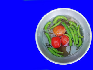 Vegetables potatoes and green chili peppers in a bowl green background