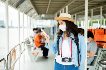 Asian woman wearing face mask when traveling and take photo by boat transportation to prevent covid19 virus infection.Tourist female using smartphone search for route location hotel at thailand