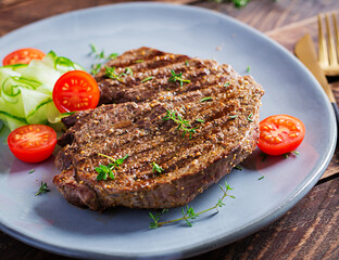 Grilled juicy steak medium rare beef with spices and fresh salad.