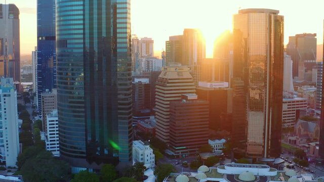 High-rise Buildings And Ferry Terminal Backlit By The Sunset In Brisbane Central Business District, QLD, Australia. - aerial drone shot