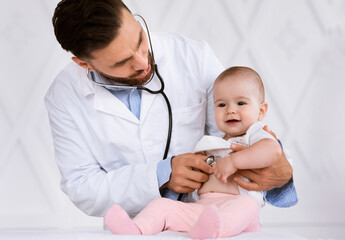 Doctor Examining Baby Listening To Heartbeat With Stethoscope In Clinic