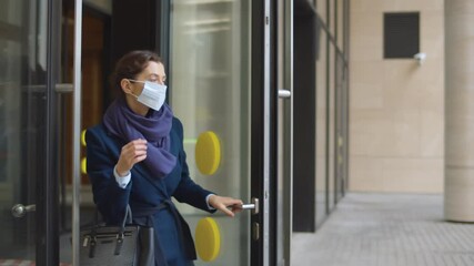Business lady leaving office building and removing safety mask outdoors