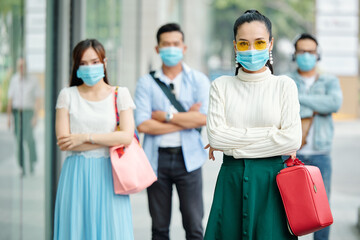 Pretty elegant young woman in medical mask standing outdoors