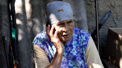 Fototapeta na wymiar Slavic senior rural woman using phone at village