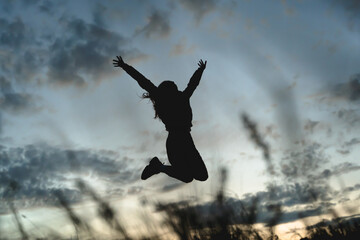 silhouette of a girl jumping against a sunset background,