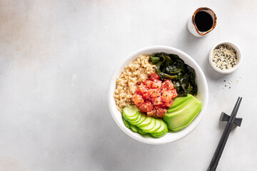 bowl with salmon, quinoa, wakame seaweed, avocado and cucumber on gray background. Food concept poke bowl. Top view. space for text