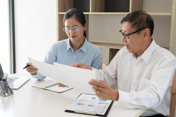 Fototapeta premium Senior and young businessman colleagues discuss online project to learning new skills or Coaching Business Team with young intern looking at pc screen in the office.
