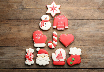 Christmas tree shape made of delicious decorated gingerbread cookies on wooden table, flat lay