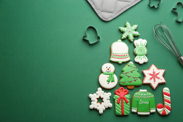 Kitchen utensils near Christmas tree shape made of delicious gingerbread cookies on green...