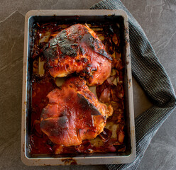 oven baked roast pork on a baking tray on dark table background