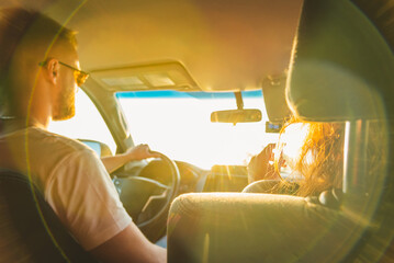 A man and his girlfriend in a car travel the world on a sunny day