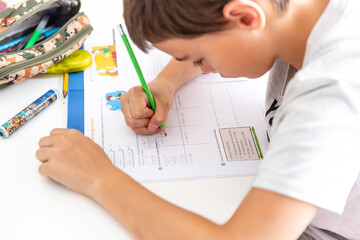 Boy studying and doing homework sitting at his desk in his bedroom at home