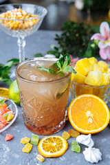 Cold refreshing pineapple cocktail with lime and mint for a hot summer day on a gray background decorated with candied fruit, mint and pineapple cubes. mojito idea, homemade lemonade with ice cubes