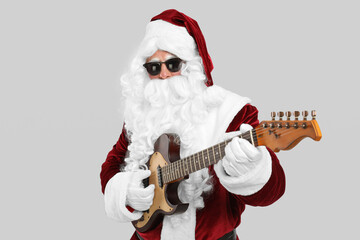 Santa Claus playing electric guitar on light grey background. Christmas music