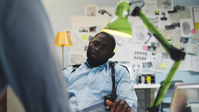 African police office sitting at desk questioning witness at police station
