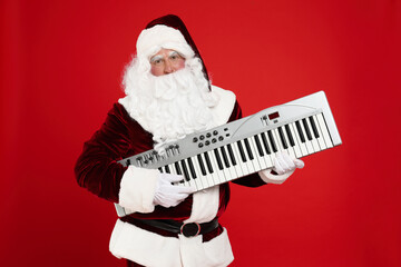 Santa Claus with synthesizer on red background. Christmas music