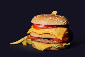 Juicy Burger with fries. Not a healthy food with a high calorie content. Dark background.