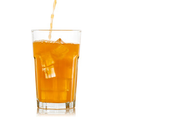 Orange juice is poured into a glass with ice cubes