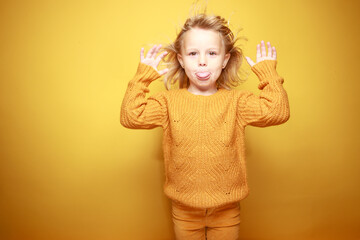 Petite fille qui fait des grimaces sur un fond jaune