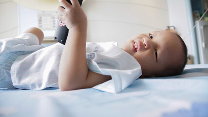 Youg Boy Resting on Hopsital bed with remote in hand as he is in qurintine during global pandemic