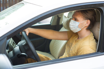 young male driving a car wearing a medical mask