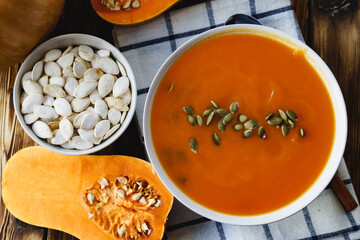 Top view of pureed pumpkin soup in a white bowl on dark table