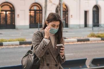 Fototapeta premium mujer con mascarilla tomando chocolate caliente en la calle
