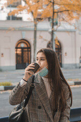 mujer con mascarilla tomando chocolate caliente en la calle