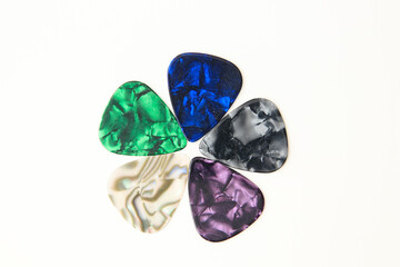 Colorful guitar picks arranged in a flower-like pattern on a white background