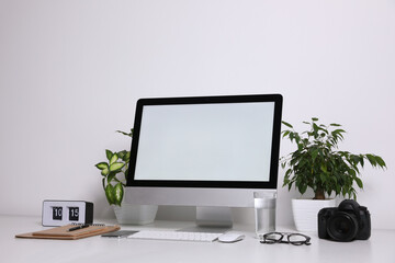 Comfortable workplace with modern computer on table near white wall. Space for text