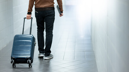 Travel insurance concept. Male tourist carrying suitcase luggage and digital tablet walking in...