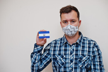 Man in checkered shirt show El Salvador flag card in hand, wear protect mask isolated on white background. American countries Coronavirus concept.