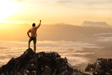Success male hiker with arms outstretched on top of mountain