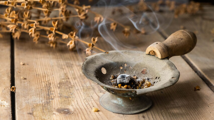 Incense burner on a wooden table. 
Walnut and basil in the background