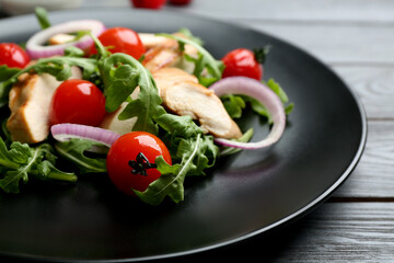 Delicious salad with chicken, vegetables and arugula  on grey table, closeup