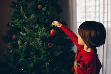 Child decorating the tree seen from behind