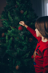 Child decorating the tree seen from behind