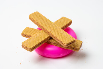 Delicious vanilla wafer stacks on a pink plastic  tube isolated on white background