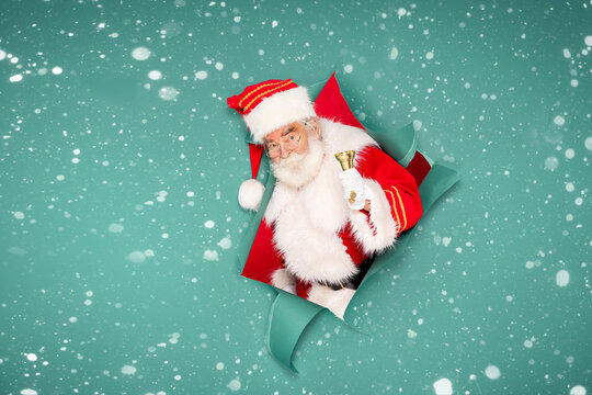 Cheerful real Santa Claus ringing a golden bell.